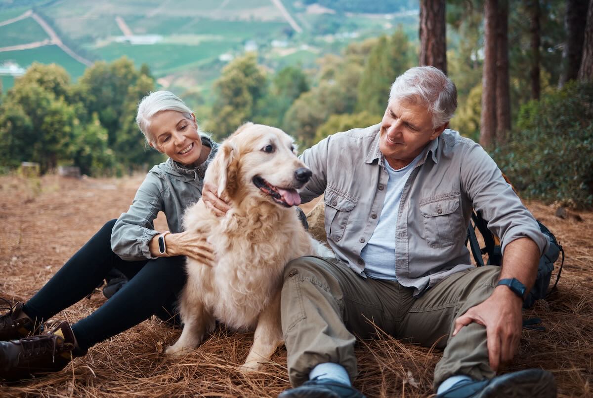 Mature couple resting with their dog during a hike