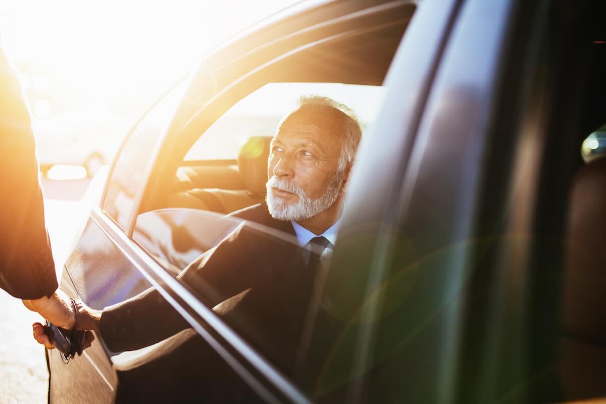 Senior man sitting at a back of a car, a close up 